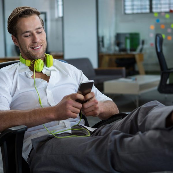 Smiling businessman using mobile phone in office